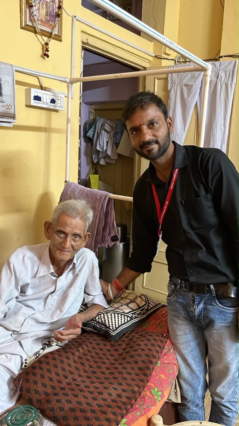 An Advino caregiver standing beside an elderly man at a board game in his home.